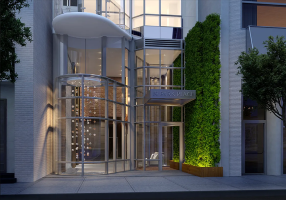 Front view of a modern building entrance with glass facade and a vertical garden.