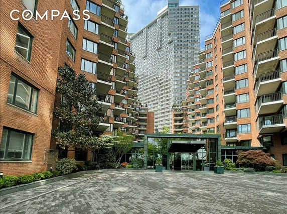 Front view of a multi-story apartment complex with a central entrance and balconies.