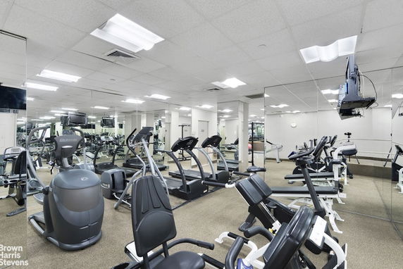 Interior view of a fitness gym with exercise equipment and mirrors on the walls.