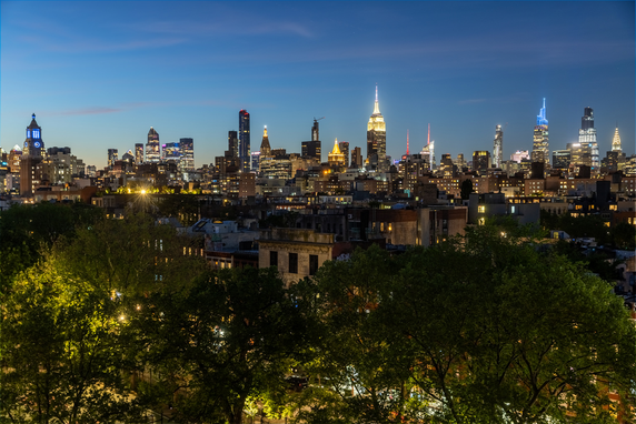 Panoramic view of a city skyline at dusk with illuminated skyscrapers.