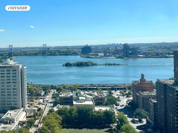 View of buildings and a river with a bridge and island in the distance.