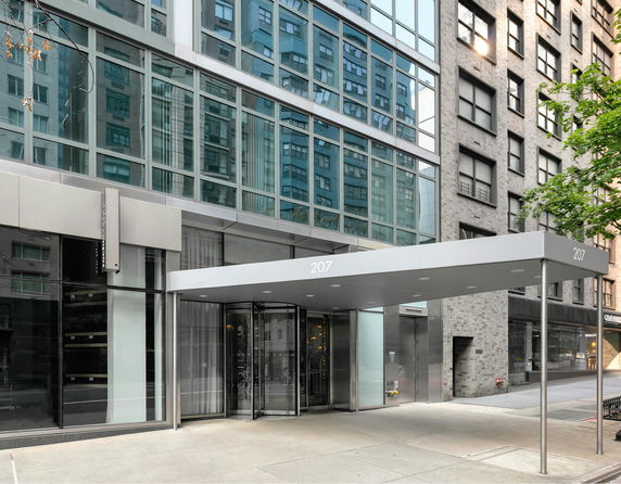 Street-level view of a modern building entrance with glass facade.
