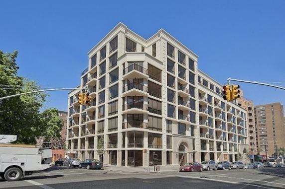 Front view of a multi-story building with modern glass balconies at a street corner.
