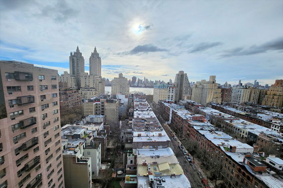 Panoramic view of an urban area with high-rise buildings and a river in the distance.