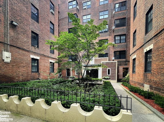 Front view of a multi-story brick apartment building with a courtyard.