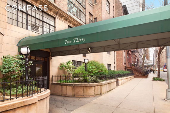 Front view of a building with a green canopy entrance and large windows.
