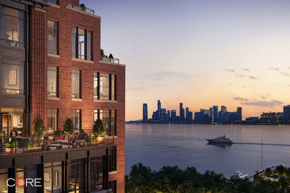 Partial view of a brick building with a waterfront view of a city skyline at dusk.