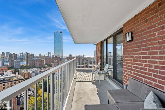 Balcony with a view of cityscape, featuring skyscrapers and a river in the background.