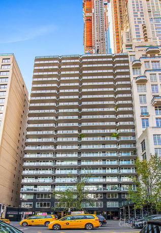 Front view of a multi-story building with balconies and glass windows.