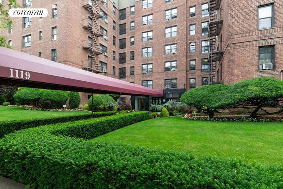 Front view of a brick apartment building with a red canopy entrance.