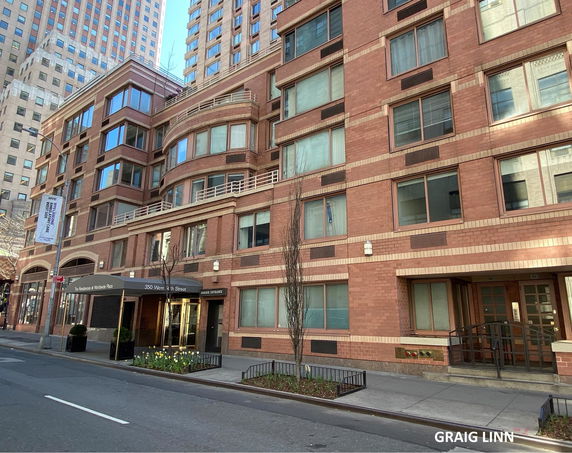 Front view of a multi-story brick building with large windows and a main entrance awning.