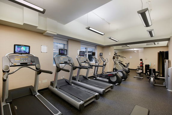 Interior view of a gym with several treadmills and exercise machines.