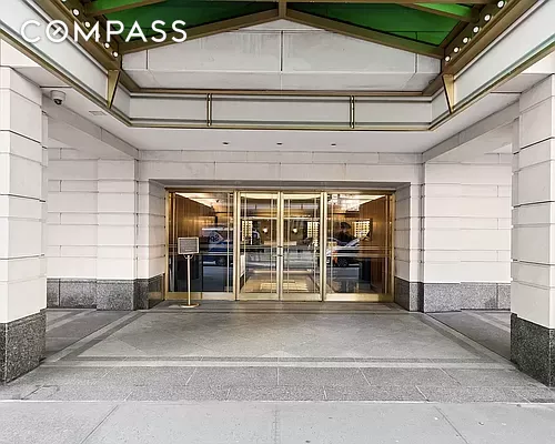Front entrance of a building with revolving glass doors and a covered entryway.