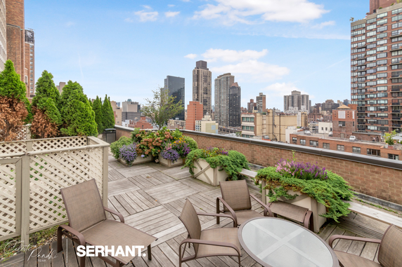 Rooftop patio with seating area and cityscape view.