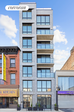 Front view of a multi-story residential building with large windows and balconies.