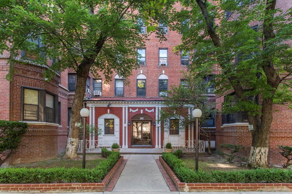 Front view of a multi-story brick building with decorative white arches over windows.