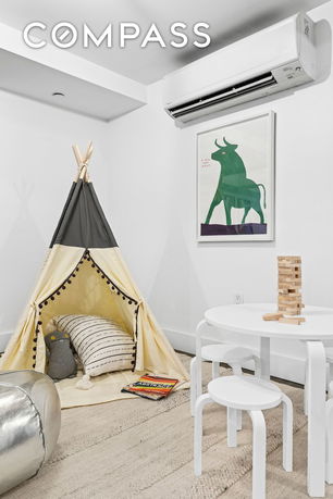 Indoor play area with a children's tent, round table, and a drawing on the wall.