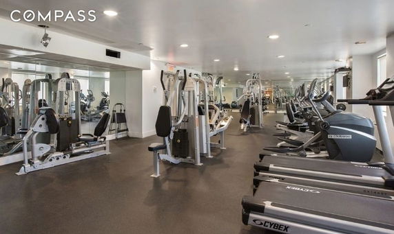 Indoor gym area with various exercise equipment and machines.