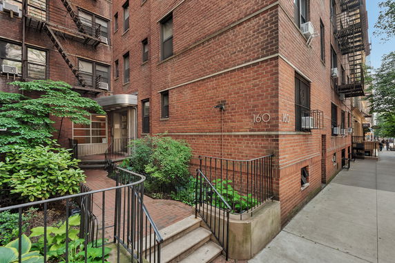 Front view of a multi-story brick apartment building with a small entrance walkway.