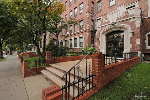 Front view of a multi-story brick building with a decorative entrance and stairs.