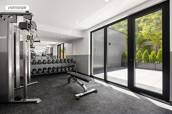 Indoor gym area with exercise equipment and a large glass door leading outside.