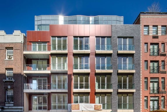 Front view of a modern multi-story building with large windows and balconies.