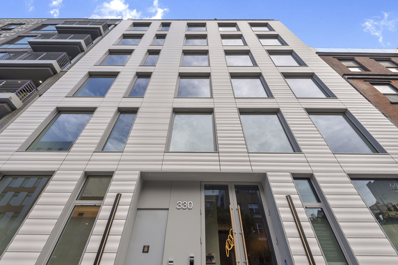 Front view of a modern multi-story building with large windows and a numbered entrance.