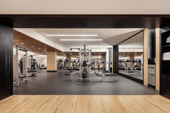 Interior of a modern gym with exercise equipment and wooden flooring.
