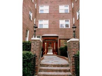 Front view of a multi-story brick building with stairs leading to the entrance.