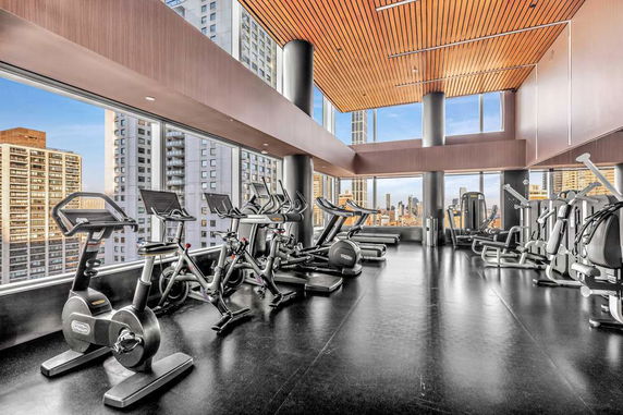 Interior view of a modern gym with large windows and exercise equipment.