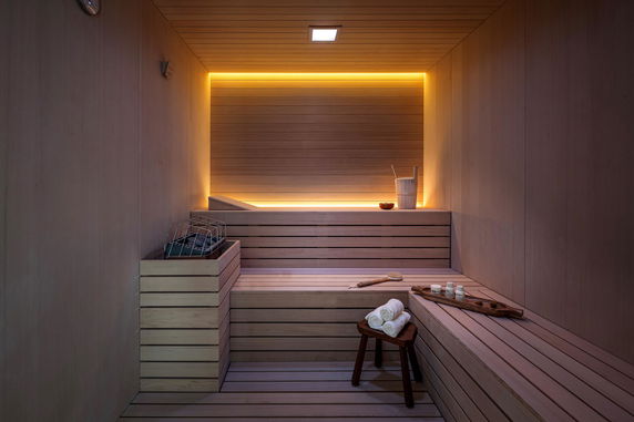 Interior view of a modern sauna room with wooden benches and ambient lighting.