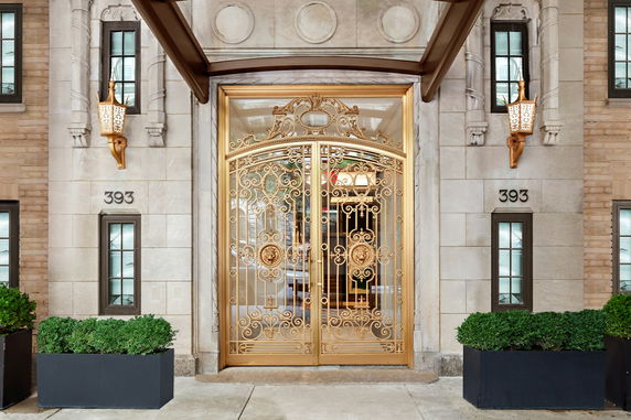 Front view of a building entrance with ornate golden doors and decorative lighting.