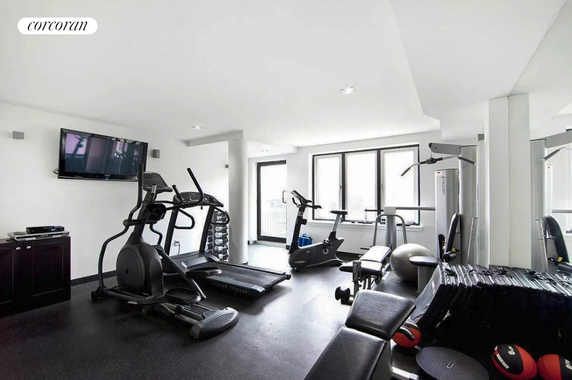 Indoor gym area with exercise equipment and a mounted TV.