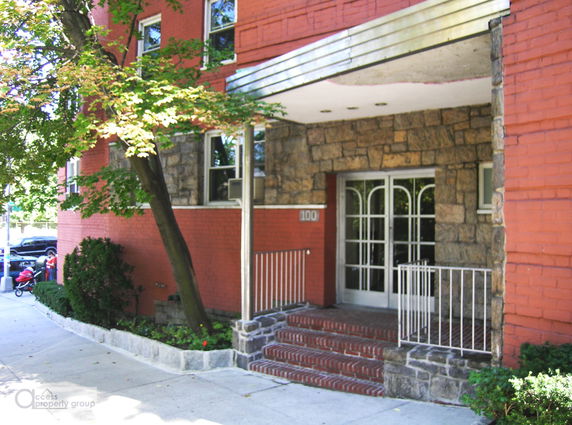 Front view of a red brick building with stone accents and a metal awning above the entrance.