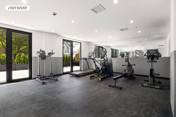 Indoor gym area with exercise equipment and large windows.