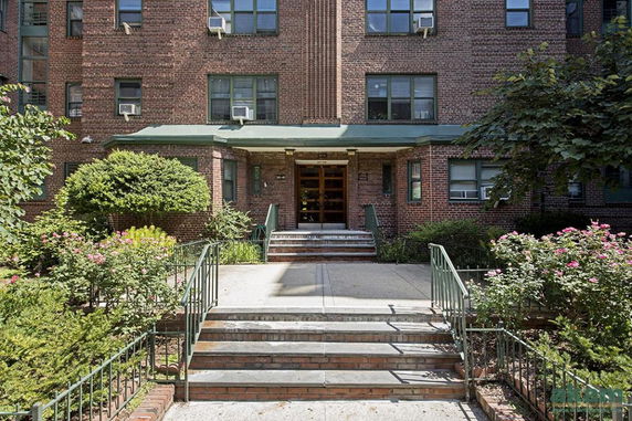 Front view of a multi-story brick building with stairs leading to the entrance.