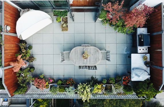 Rooftop patio with dining table, plants, and a barbecue grill.