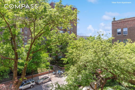 View from an apartment showcasing trees and adjacent brick buildings.