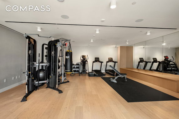 Home gym with workout equipment and mirrors on the wall.