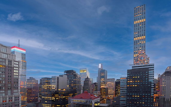 Skyline view of multiple skyscrapers at dusk with illuminated windows.