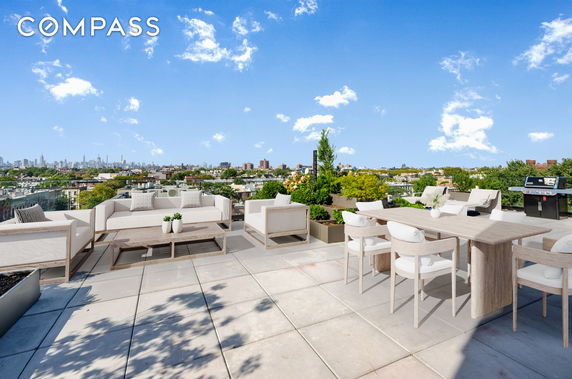 Rooftop with lounge seating, dining table, and city skyline view.