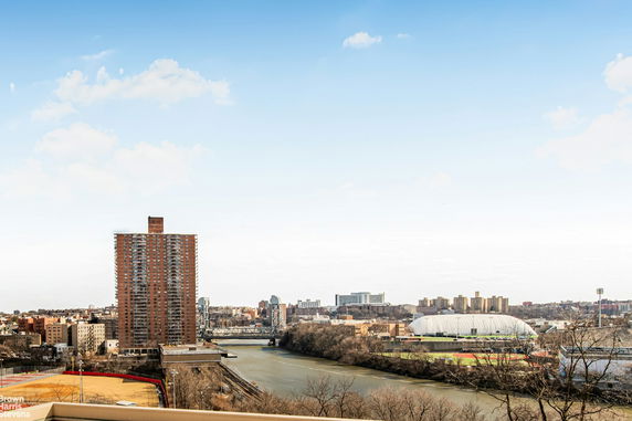 View of a cityscape with a river, high-rise buildings, and a stadium.