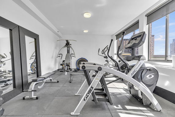 Indoor gym area with exercise equipment and large mirrors on the wall.