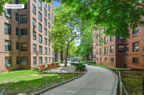 View of multi-story brick residential buildings with trees and a walking path.