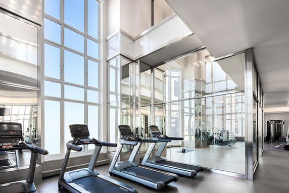 Interior view of a modern fitness club area with treadmills and large windows.