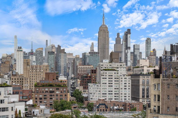 Panoramic view of a city skyline with numerous skyscrapers under a partly cloudy sky.