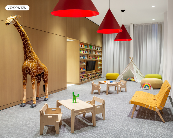 Indoor play area with children's furniture, a stuffed giraffe, and a bookshelf filled with books.