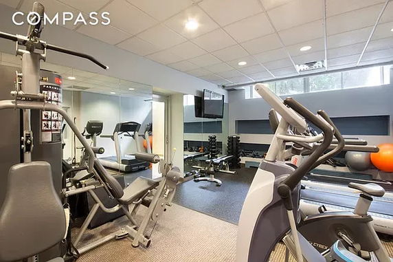 Indoor gym area with various exercise equipment including machines and weights.