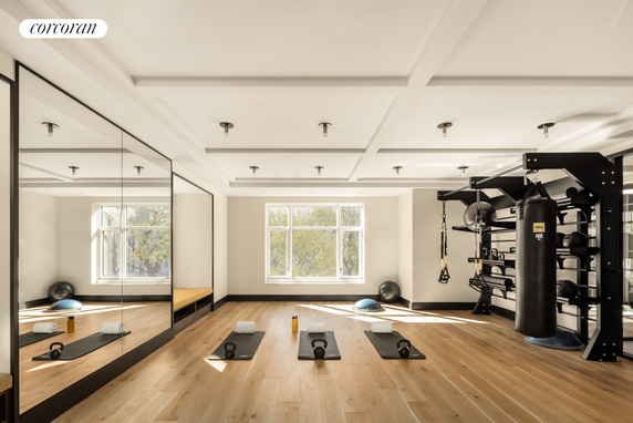 Room with exercise equipment including punching bag and exercise mats.
