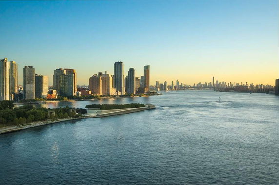 Panoramic view of a cityscape along a river with multiple high-rise buildings.